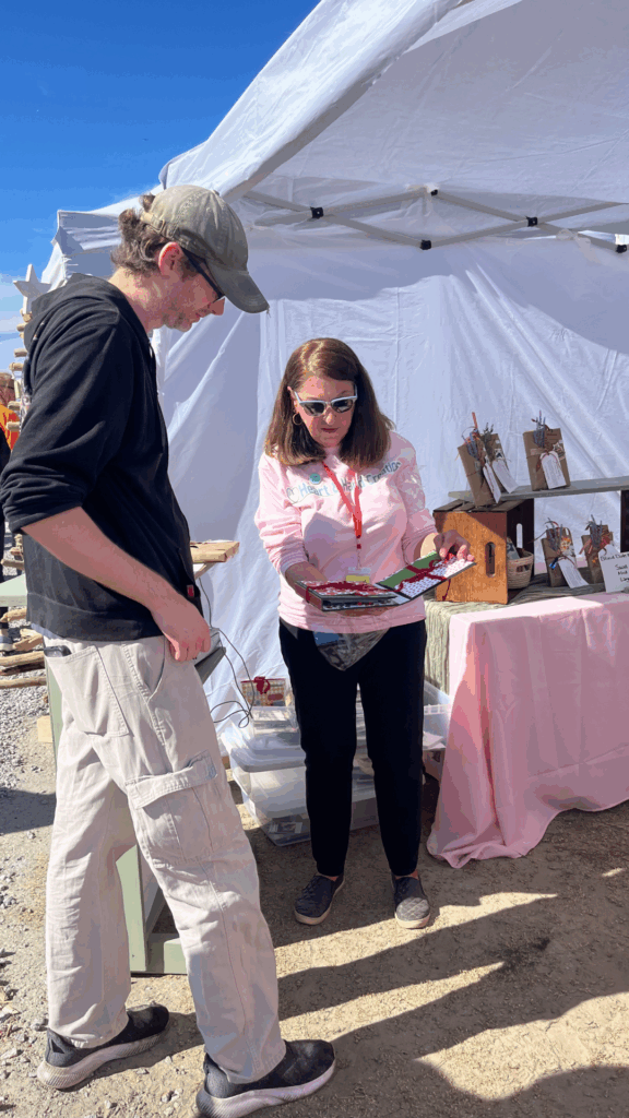 Me, a vendor at the Annual Holiday Market, talking to a customer about a handmade scrapbook that I created. 